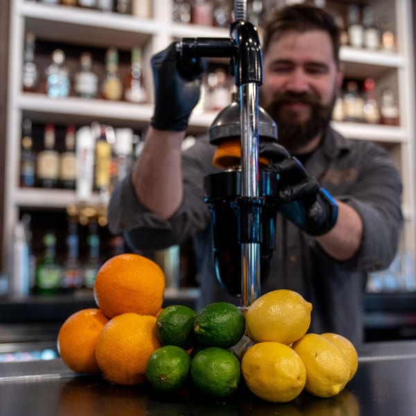 Bartender at The Cross-Eyed Cricket squeezing fresh oranges and lemons for drinks.