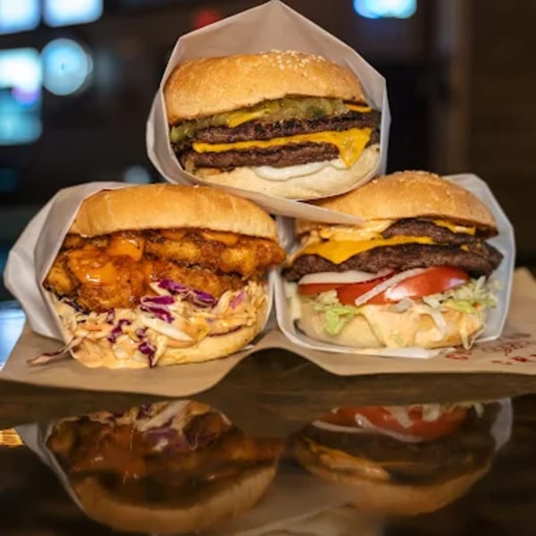 Three delicious burgers from The Cross-Eyed Cricket, including a chicken sandwich and two cheeseburgers.